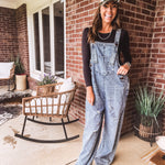 Loose fit medium wash denim overalls with adjustable button straps and sides and distressing throughout.