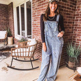 Loose fit medium wash denim overalls with adjustable button straps and sides and distressing throughout.