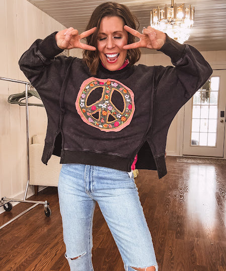 Washed charcoal pullover with exposed seams, a coral and floral peace patch on the front and split front hem.