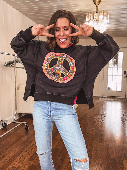 Washed charcoal pullover with exposed seams, a coral and floral peace patch on the front and split front hem.