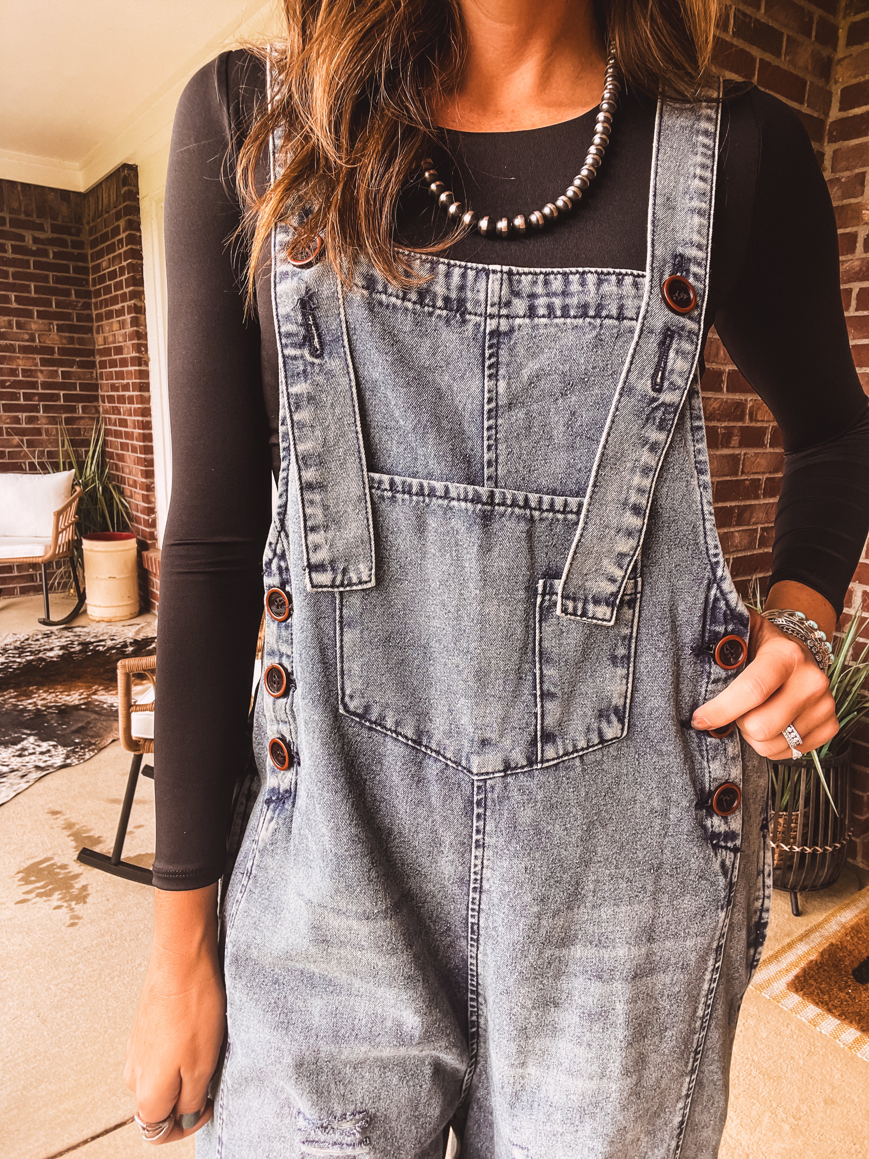 Loose fit medium wash denim overalls with adjustable button straps and sides and distressing throughout.