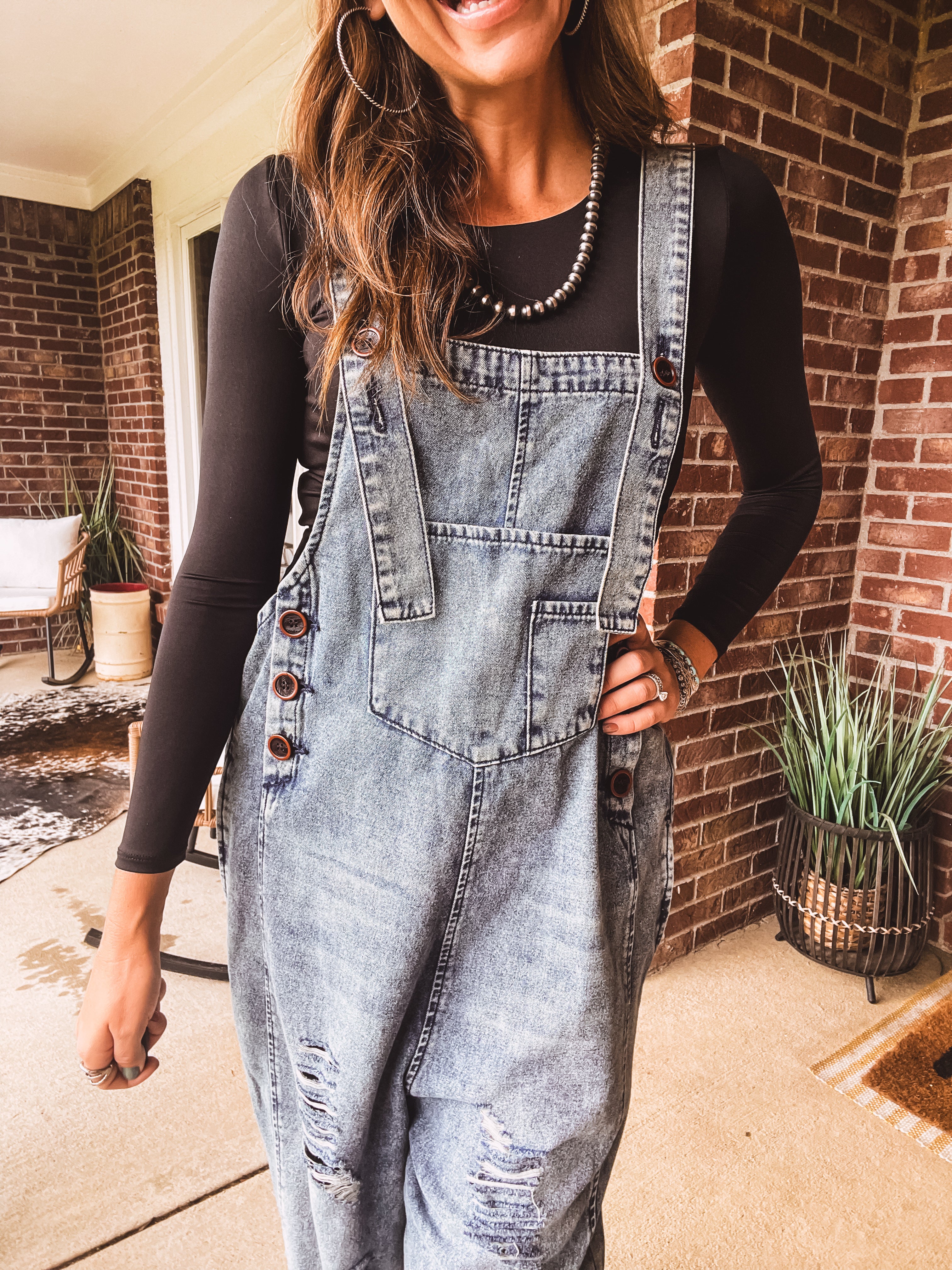 Loose fit medium wash denim overalls with adjustable button straps and sides and distressing throughout.