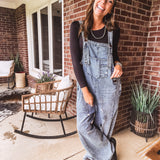 Loose fit medium wash denim overalls with adjustable button straps and sides and distressing throughout.