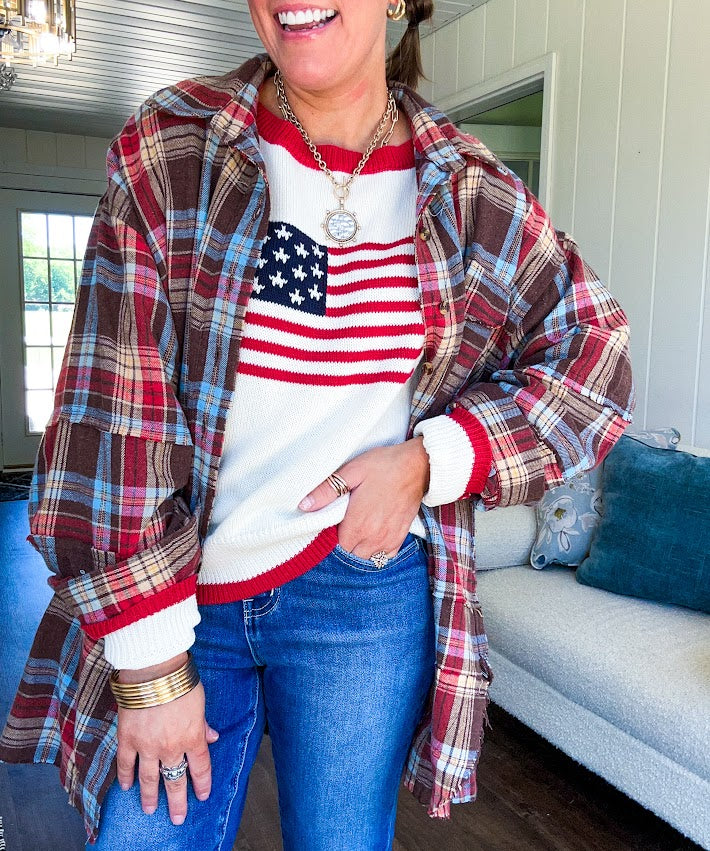 Cream long sleeved sweater with round neck and red trim at neck an cuffs with American Flag motif.