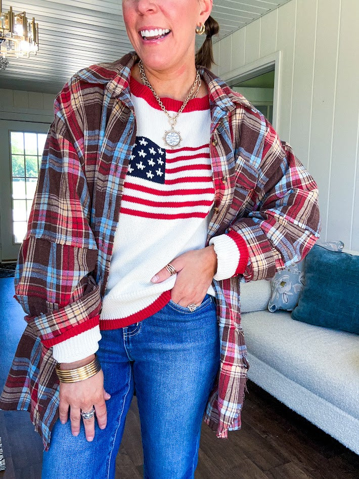 Cream long sleeved sweater with round neck and red trim at neck an cuffs with American Flag motif.