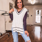 Cream cable knit open sided vest with wide V neck and navy trim at the neck and wide hem with side ties.