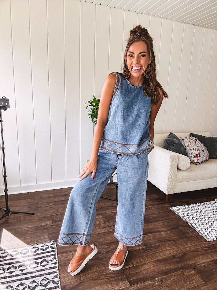 Light wash denim set that's equal parts effortless and eye-catching. The tank features a hook-and-eye neck closure and loose hem, while caramel embroidered stitching adds personality throughout. Pair it with the matching wide-leg pants—complete with button-zip closure, elastic back waist, front and side pleating, and pockets lined with the same playful embroidered detail.