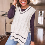Cream cable knit open sided vest with wide V neck and navy trim at the neck and wide hem with side ties.