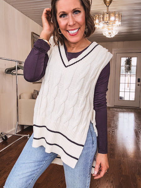 Cream cable knit open sided vest with wide V neck and navy trim at the neck and wide hem with side ties.