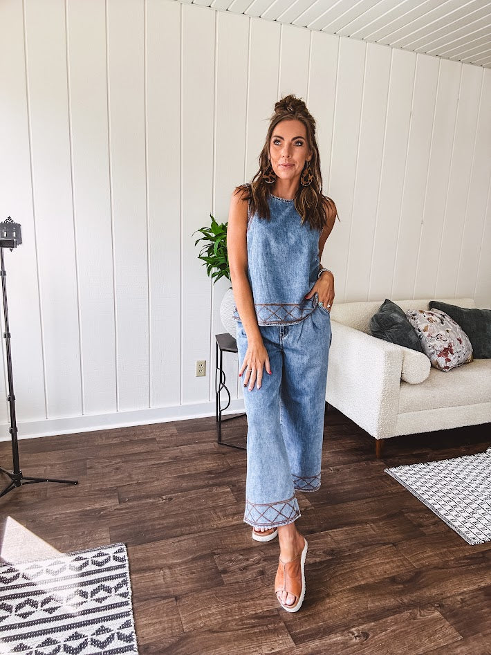 Light wash denim set that's equal parts effortless and eye-catching. The tank features a hook-and-eye neck closure and loose hem, while caramel embroidered stitching adds personality throughout. Pair it with the matching wide-leg pants—complete with button-zip closure, elastic back waist, front and side pleating, and pockets lined with the same playful embroidered detail.