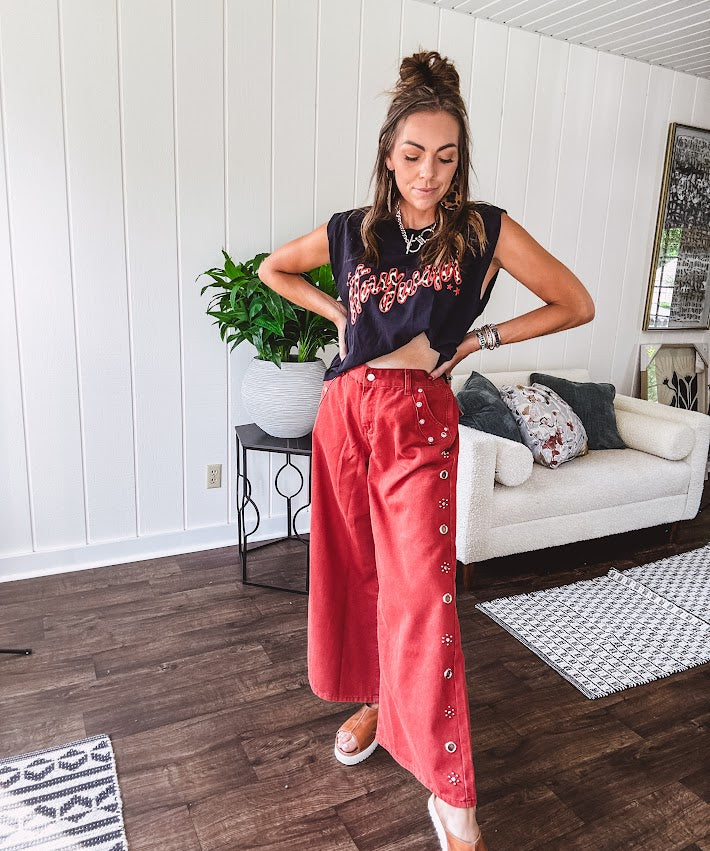 These vintage-inspired wide leg pants are a total vibe—low-rise silhouette with playful silver eyelets and studs running down the sides that catch the light just right. Crafted from lightweight 100% cotton denim with that perfect worn-in wash. The button and zipper closure with elastic back waist keeps them comfortable all day long. Ultra-wide legs that make a statement.