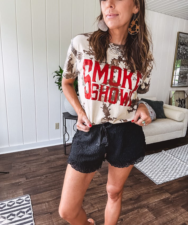 100% Cotton  tee with bold red "Smoke Show" graphic against an artistic tan and brown paint splatter backdrop.