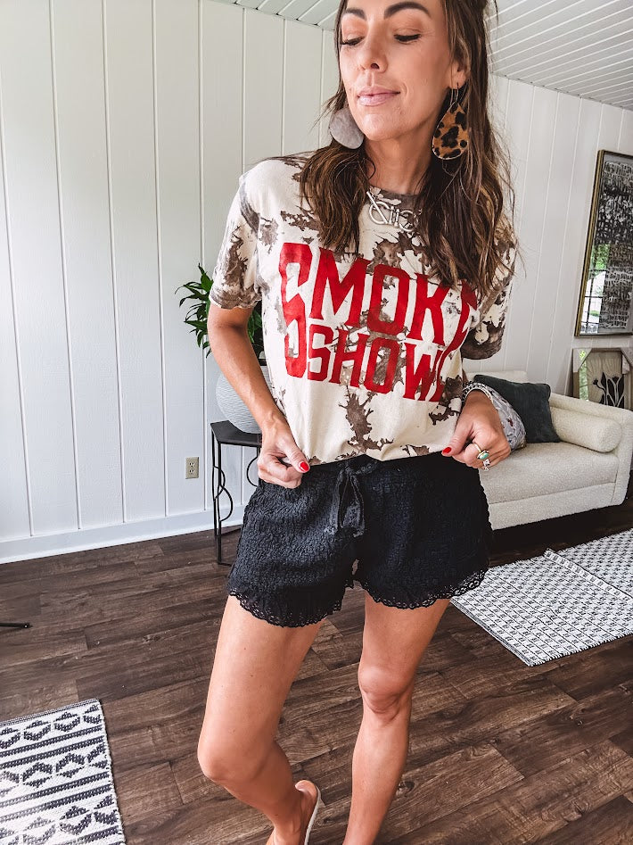 100% Cotton  tee with bold red "Smoke Show" graphic against an artistic tan and brown paint splatter backdrop.