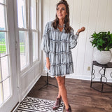 Soft, lightweight Tencel denim mini dress in a retro acid wash design with a V neck and mock collar and tiered design with long sleeves and elastic cuffs each tier and the mock neck feature raw seams and it has pockets.