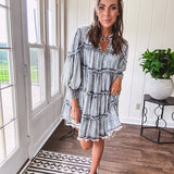 Soft, lightweight Tencel denim mini dress in a retro acid wash design with a V neck and mock collar and tiered design with long sleeves and elastic cuffs each tier and the mock neck feature raw seams and it has pockets.