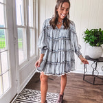 Soft, lightweight Tencel denim mini dress in a retro acid wash design with a V neck and mock collar and tiered design with long sleeves and elastic cuffs each tier and the mock neck feature raw seams and it has pockets.