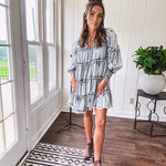Soft, lightweight Tencel denim mini dress in a retro acid wash design with a V neck and mock collar and tiered design with long sleeves and elastic cuffs each tier and the mock neck feature raw seams and it has pockets.