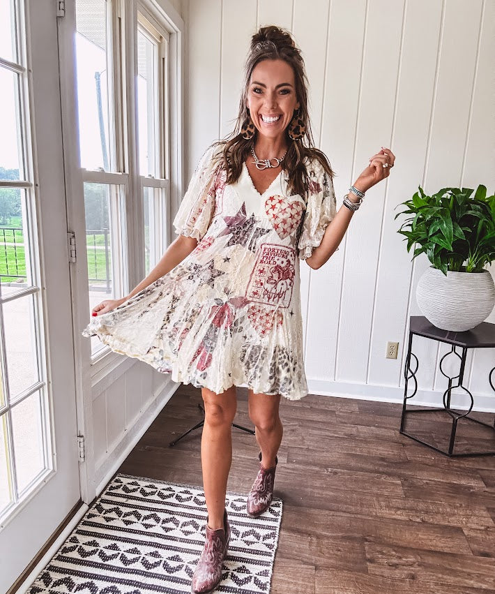 Cream V-neck mini dress with red, taupe, and leopard hearts and stars, lace overlay, ruffled puff sleeves, and an elastic hem. The stretchy, flowy silhouette flatters and flows.