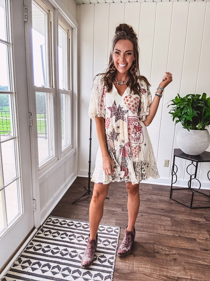 Cream V-neck mini dress with red, taupe, and leopard hearts and stars, lace overlay, ruffled puff sleeves, and an elastic hem. The stretchy, flowy silhouette flatters and flows.