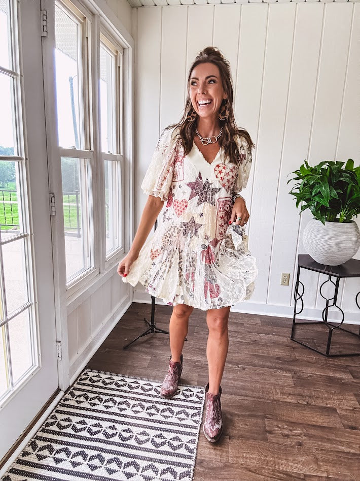 Cream V-neck mini dress with red, taupe, and leopard hearts and stars, lace overlay, ruffled puff sleeves, and an elastic hem. The stretchy, flowy silhouette flatters and flows.