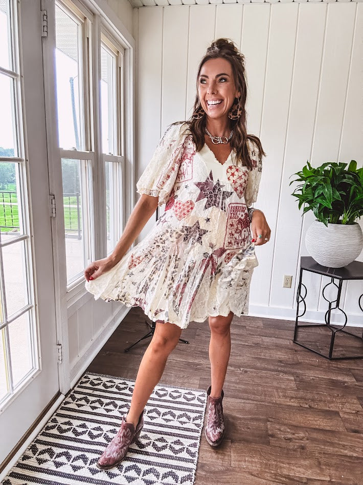 Cream V-neck mini dress with red, taupe, and leopard hearts and stars, lace overlay, ruffled puff sleeves, and an elastic hem. The stretchy, flowy silhouette flatters and flows.