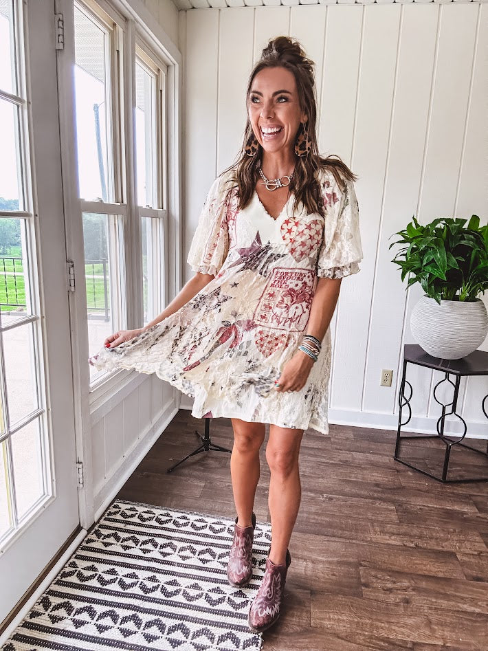 Cream V-neck mini dress with red, taupe, and leopard hearts and stars, lace overlay, ruffled puff sleeves, and an elastic hem. The stretchy, flowy silhouette flatters and flows.