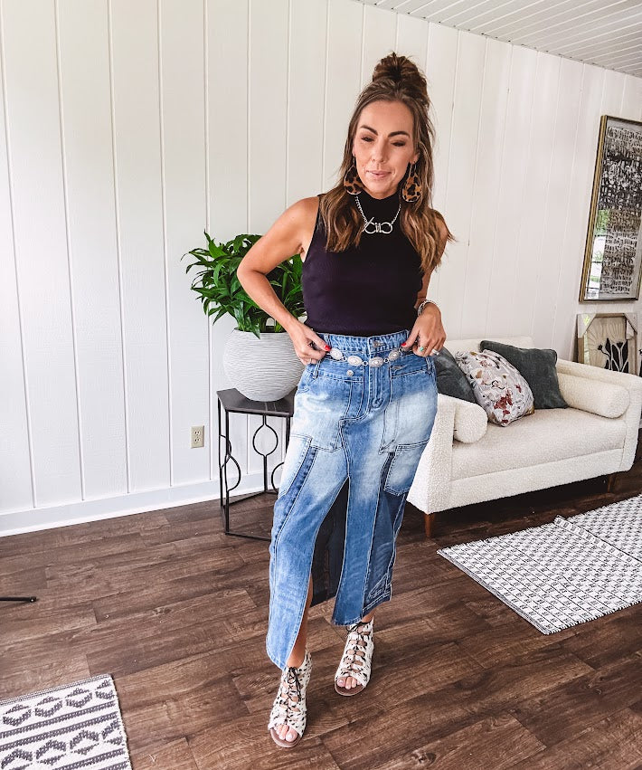 Medium wash midi skirt featuring light and dark wash details throughout with a button and zipper closure and elastic back waist, high front split, side pockets and an upside down design on the bottom. 