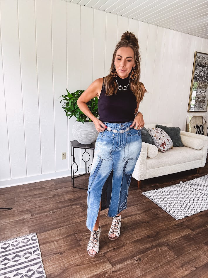 Medium wash midi skirt featuring light and dark wash details throughout with a button and zipper closure and elastic back waist, high front split, side pockets and an upside down design on the bottom. 