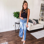 Medium wash midi skirt featuring light and dark wash details throughout with a button and zipper closure and elastic back waist, high front split, side pockets and an upside down design on the bottom. 