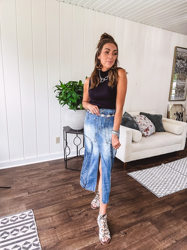 Medium wash midi skirt featuring light and dark wash details throughout with a button and zipper closure and elastic back waist, high front split, side pockets and an upside down design on the bottom. 