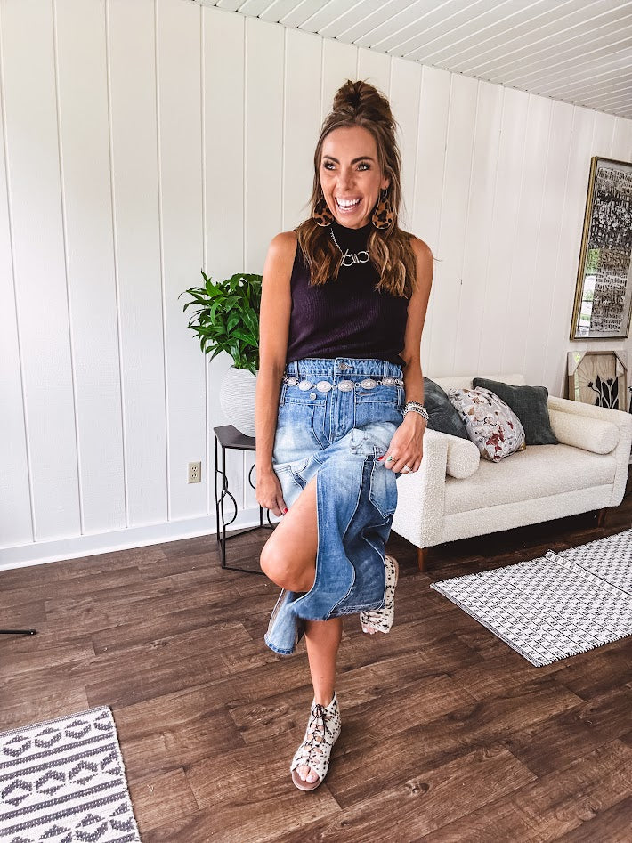 Medium wash midi skirt featuring light and dark wash details throughout with a button and zipper closure and elastic back waist, high front split, side pockets and an upside down design on the bottom. 