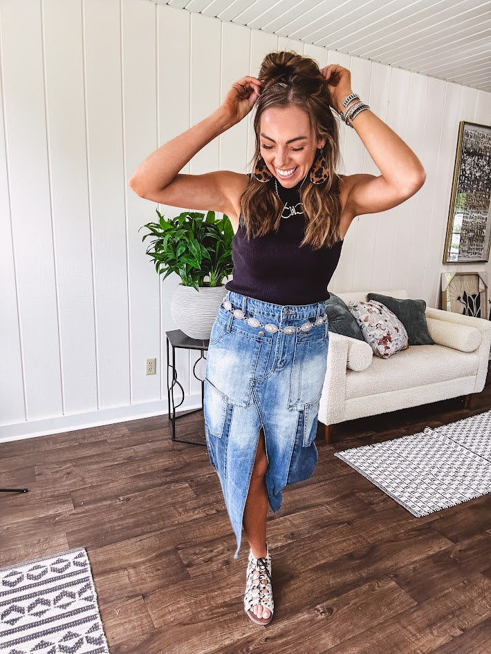 Medium wash midi skirt featuring light and dark wash details throughout with a button and zipper closure and elastic back waist, high front split, side pockets and an upside down design on the bottom. 