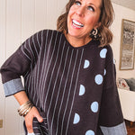Black V neck sweater with slate blue stripes on one side and polka dots on the other.