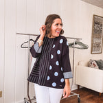 Black V neck sweater with slate blue stripes on one side and polka dots on the other.