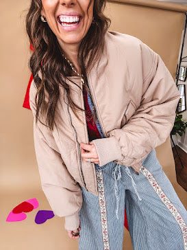 Tan puffer bomber jacket with zipper front and side pockets.