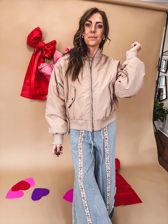 Tan puffer bomber jacket with zipper front and side pockets.