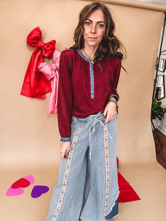 Burgundy Henley style long sleeved top with denim trim at 1/4 button down front, collar and cuffs.