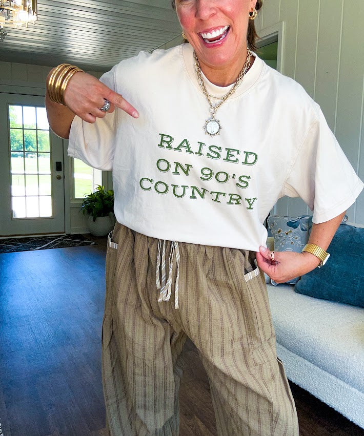 Cream cotton tee with olive "Raised On 90's Country" print on front, relaxed fit.