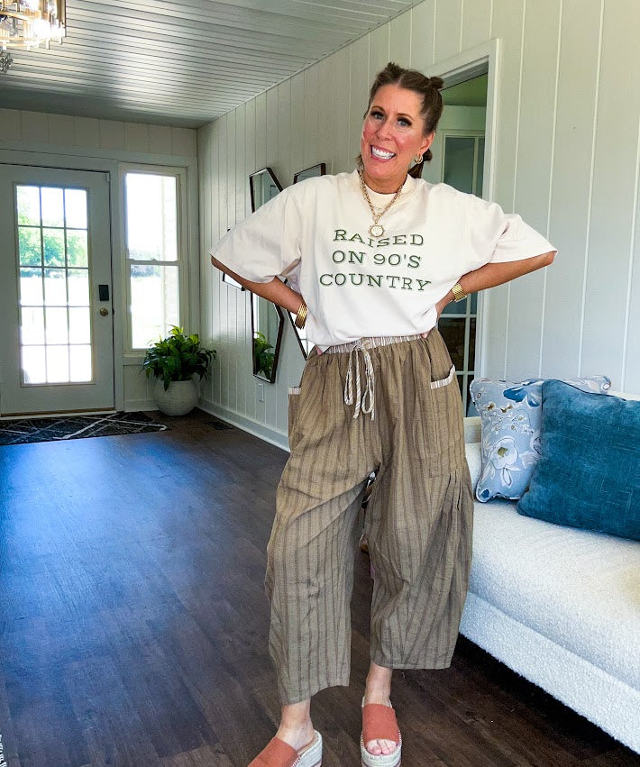 Cream cotton tee with olive "Raised On 90's Country" print on front, relaxed fit.