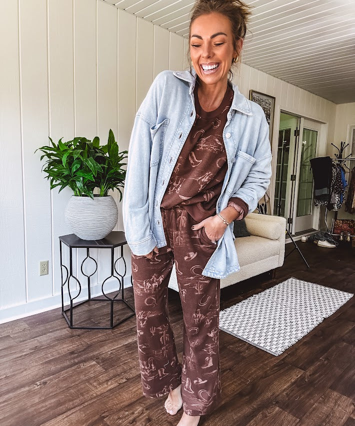 Crafted from a soft cotton-poly blend, these lightweight joggers feature an eye-catching western print complete with boots, hats, horses, and horseshoes across a warm brown base. With wide-leg silhouette, elastic drawstring waist, and functional pockets.