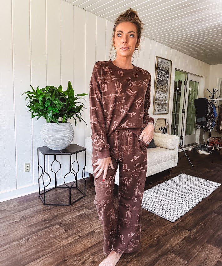 Crafted from a soft cotton-poly blend, these lightweight joggers feature an eye-catching western print complete with boots, hats, horses, and horseshoes across a warm brown base. With wide-leg silhouette, elastic drawstring waist, and functional pockets.
