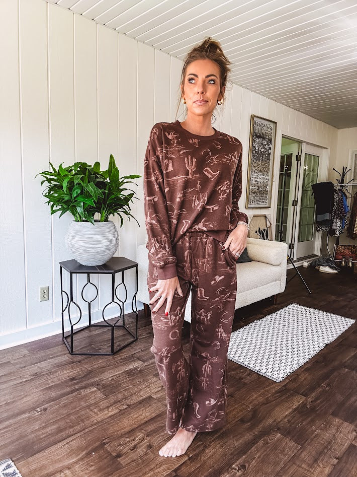 Crafted from a soft cotton-poly blend, these lightweight joggers feature an eye-catching western print complete with boots, hats, horses, and horseshoes across a warm brown base. With wide-leg silhouette, elastic drawstring waist, and functional pockets.