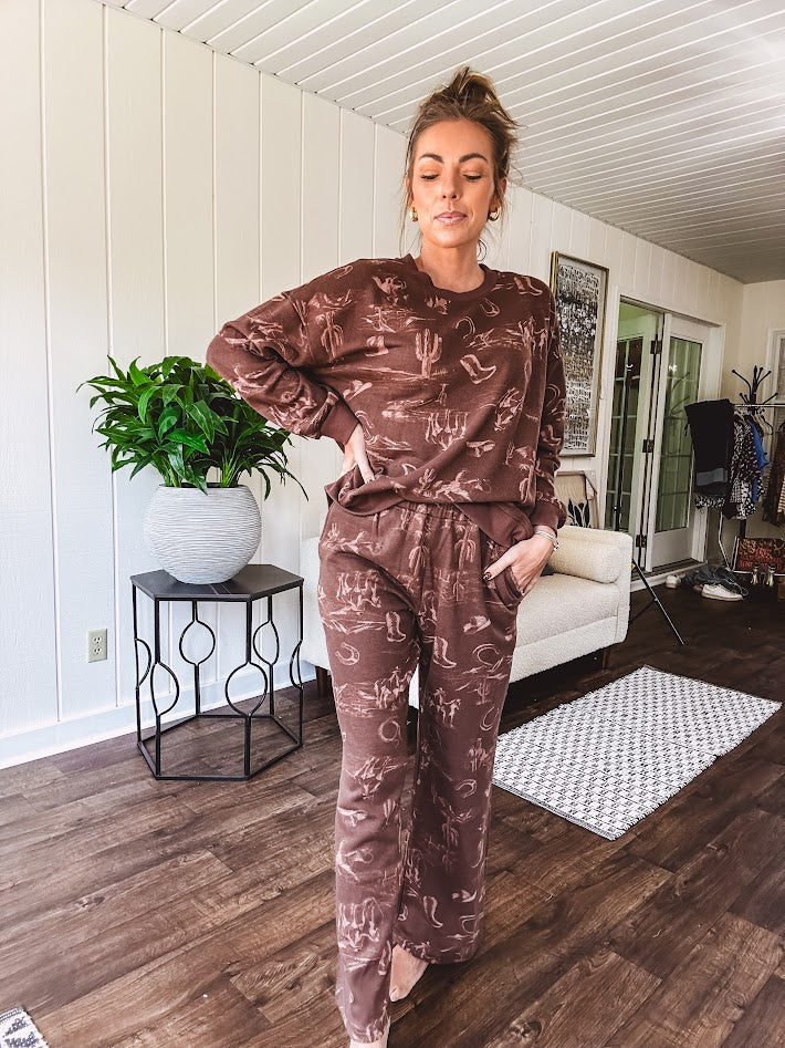 Crafted from a soft cotton-poly blend, these lightweight joggers feature an eye-catching western print complete with boots, hats, horses, and horseshoes across a warm brown base. With wide-leg silhouette, elastic drawstring waist, and functional pockets.