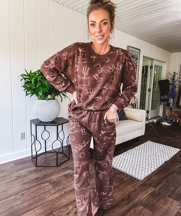 Crafted from a soft cotton-poly blend, these lightweight joggers feature an eye-catching western print complete with boots, hats, horses, and horseshoes across a warm brown base. With wide-leg silhouette, elastic drawstring waist, and functional pockets.