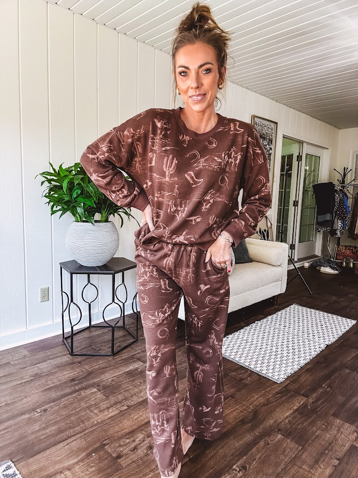Crafted from a soft cotton-poly blend, these lightweight joggers feature an eye-catching western print complete with boots, hats, horses, and horseshoes across a warm brown base. With wide-leg silhouette, elastic drawstring waist, and functional pockets.