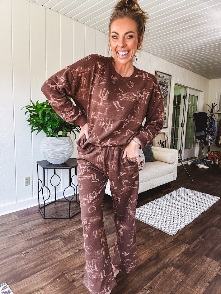 Crafted from a soft cotton-poly blend, these lightweight joggers feature an eye-catching western print complete with boots, hats, horses, and horseshoes across a warm brown base. With wide-leg silhouette, elastic drawstring waist, and functional pockets.