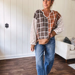 Plaid pullover pairs earth-tone mocha, cream, and rust with playful contrasting stripes on the sleeves with a split neck and relaxed fit.