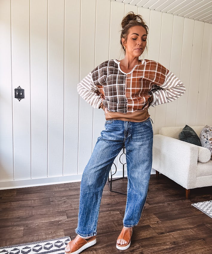 High-rise fit with a curved, architectural leg, rigid denim front, stretch fabric, top block, curved outer seam, and tapered hem that create a modern "barrel" or "horseshoe" shape sitting away from the leg.