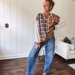 Plaid pullover pairs earth-tone mocha, cream, and rust with playful contrasting stripes on the sleeves with a split neck and relaxed fit.