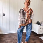 Plaid pullover pairs earth-tone mocha, cream, and rust with playful contrasting stripes on the sleeves with a split neck and relaxed fit.